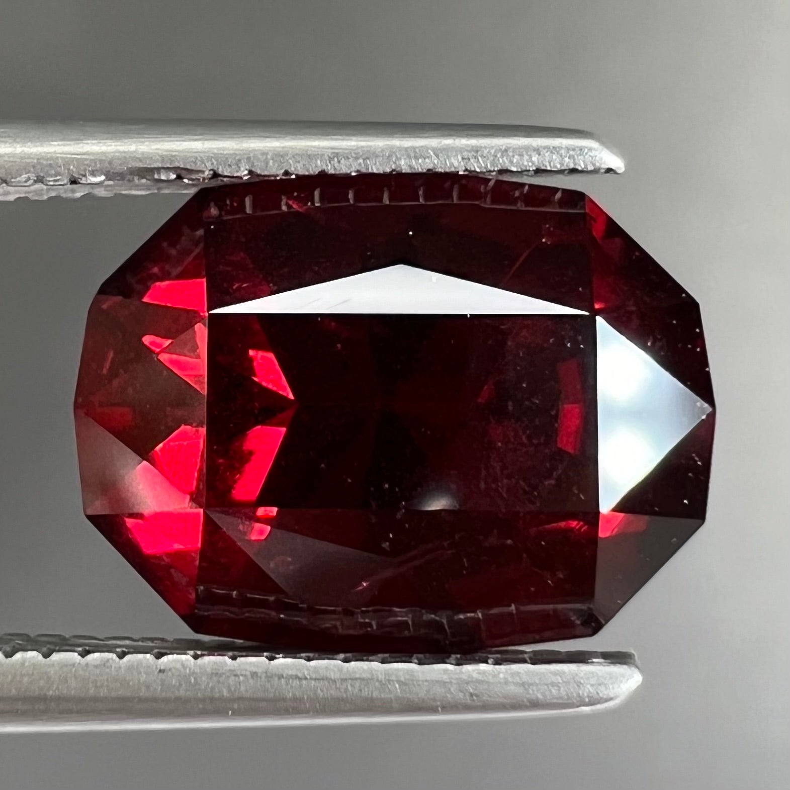 A loose, octagon cut rhodolite garnet gemstone.  The stone is a deep, purplish crimson red color.