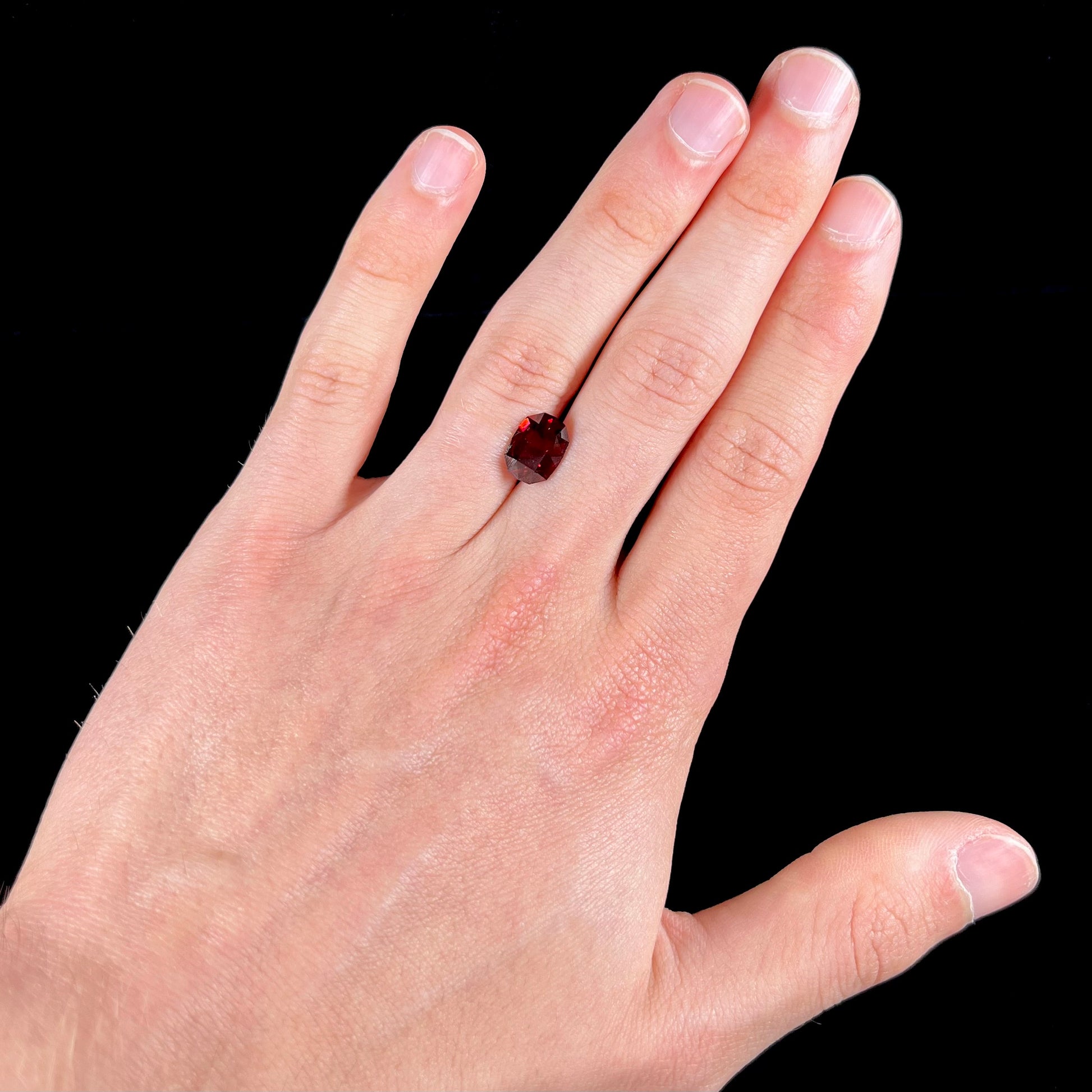 A loose, octagon cut rhodolite garnet gemstone.  The stone is a deep, purplish crimson red color.