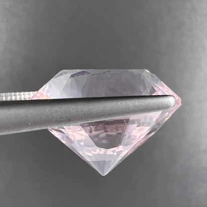 A loose, faceted oval cut rose quartz gemstone.  The stone is exceptionally clear.