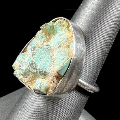 A handmade unisex sterling silver solitaire ring set with a rough, unpolished piece of turquoise stone.