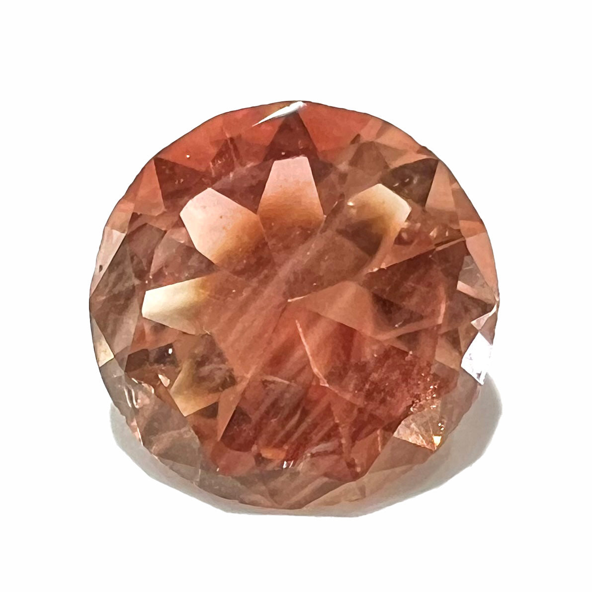 A loose, round brilliant cut Oregon sunstone gem.