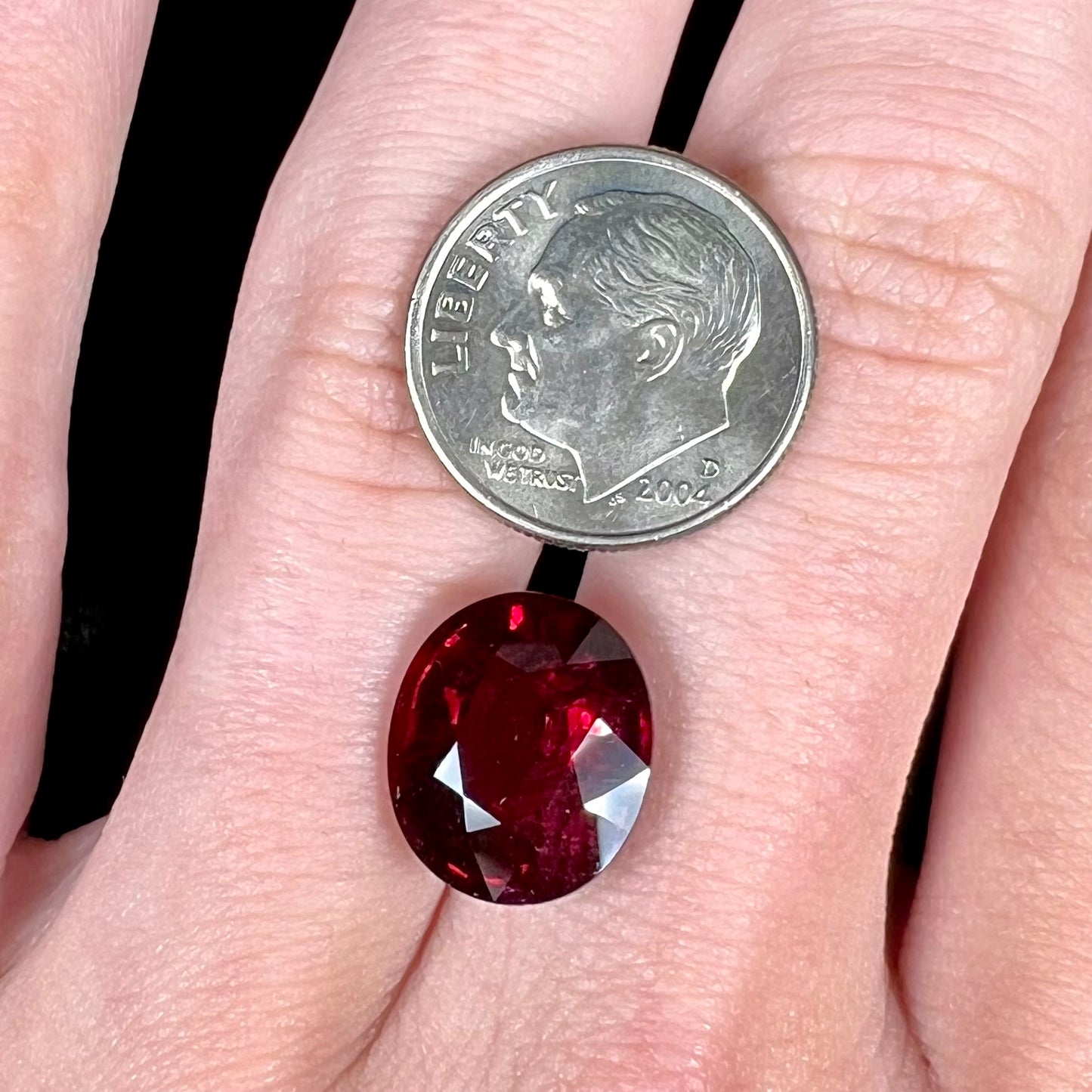 A loose, oval cut purplish red rubellite tourmaline stone.