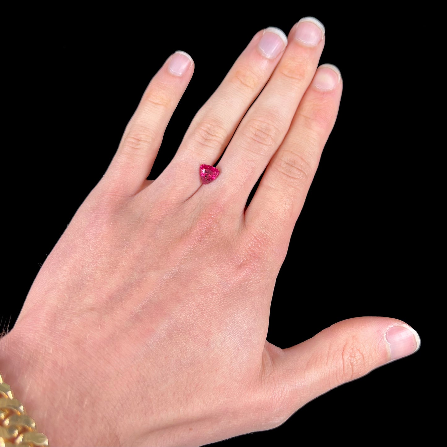 A loose, trillion cut rubellite tourmaline gemstone.