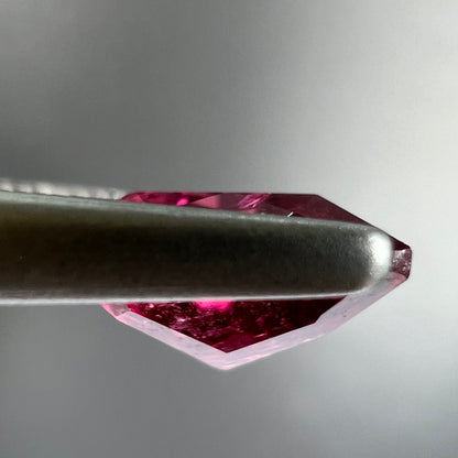 A loose, trillion cut rubellite tourmaline gemstone.