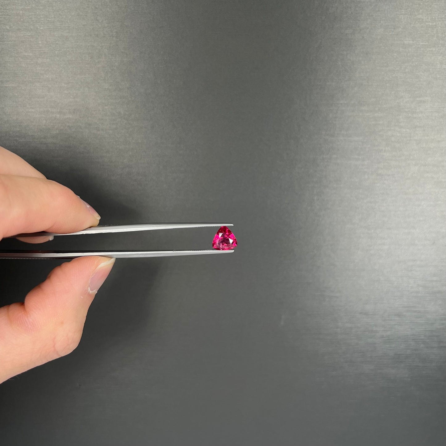A loose, trillion cut rubellite tourmaline gemstone.