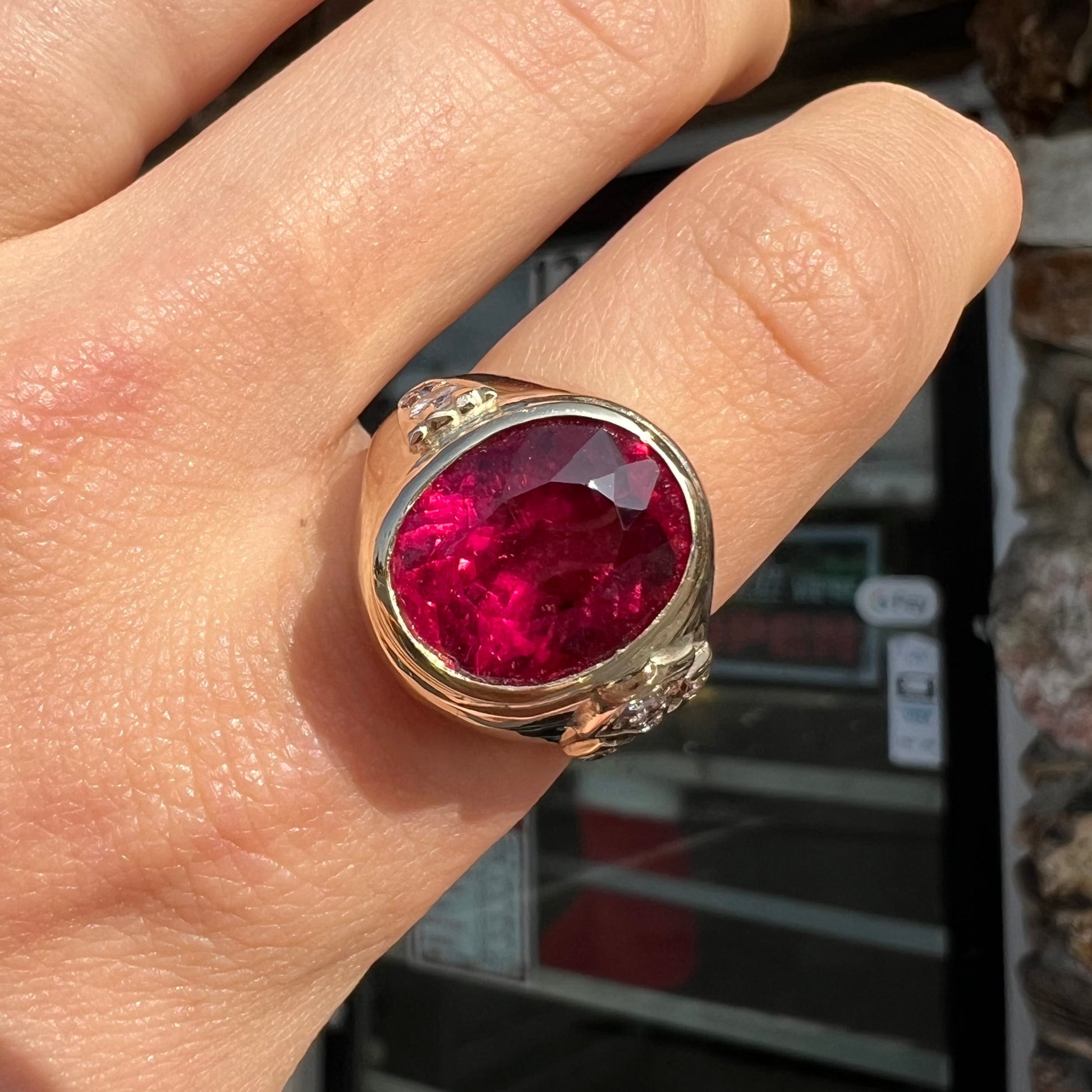 A men's yellow gold ring set with an oval cut rubellite tourmaline with diamond accents.
