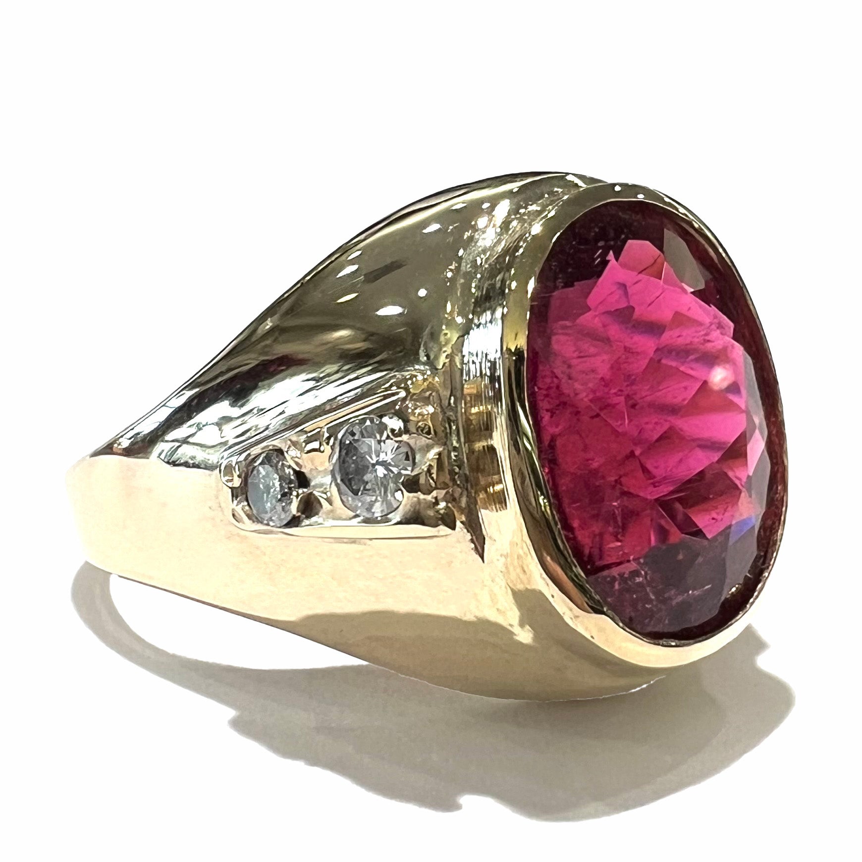 A men's yellow gold ring set with an oval cut rubellite tourmaline with diamond accents.