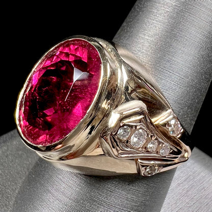 A men's yellow gold ring set with an oval cut rubellite tourmaline with diamond accents.