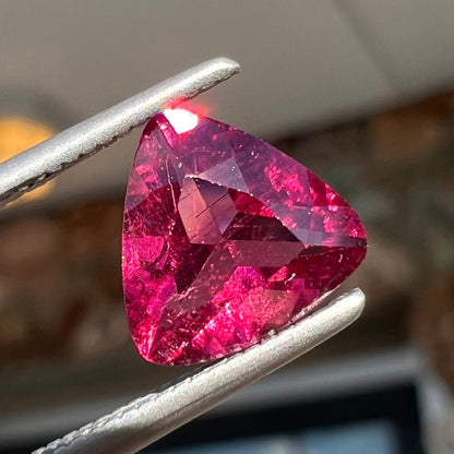 A loose, trillion cut rubellite tourmaline gemstone.