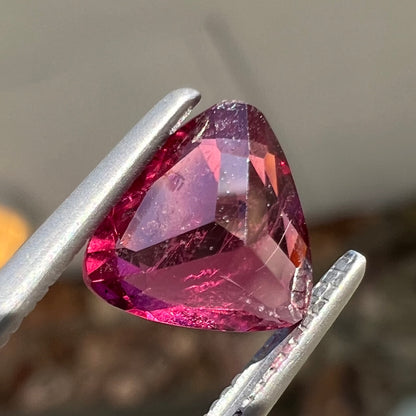 A loose, trillion cut rubellite tourmaline gemstone.