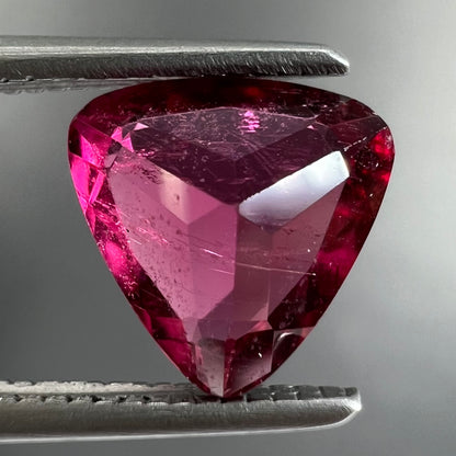 A loose, trillion cut rubellite tourmaline gemstone.