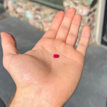 An emerald cut Burma ruby gemstone.  The stone is loose and a pinkish red color.