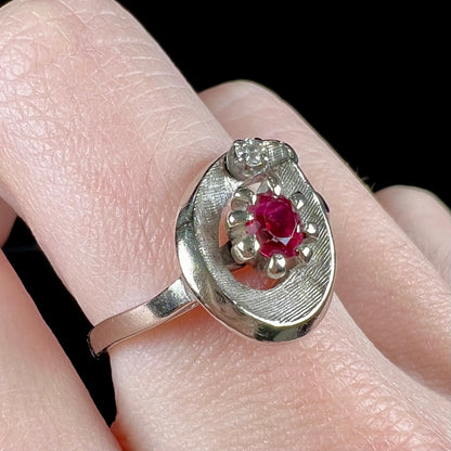 A ladies' estate white gold ruby ring set with a diamond accent stone.