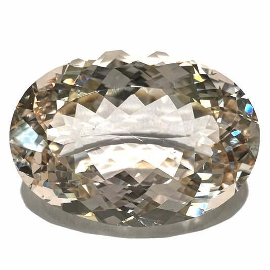 A loose, faceted oval cut kunzite gemstone.  The stone is a salmon pink color.