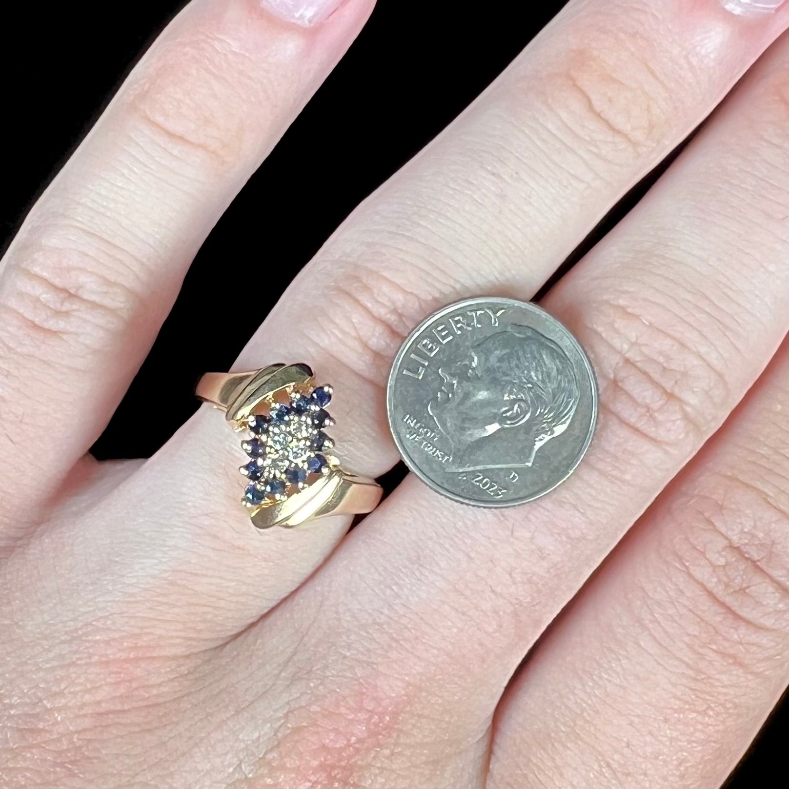 An estate, yellow gold ladies' cluster ring mounted with four round diamonds and twelve round blue sapphires.