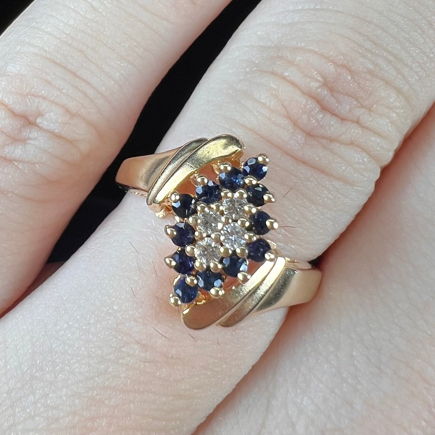 An estate, yellow gold ladies' cluster ring mounted with four round diamonds and twelve round blue sapphires.