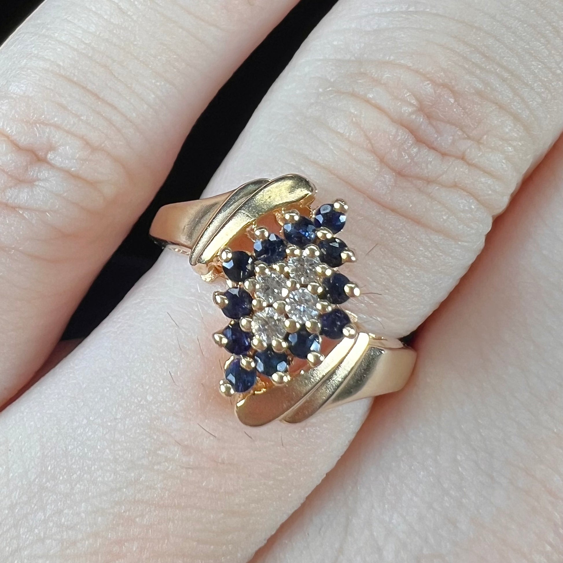 An estate, yellow gold ladies' cluster ring mounted with four round diamonds and twelve round blue sapphires.