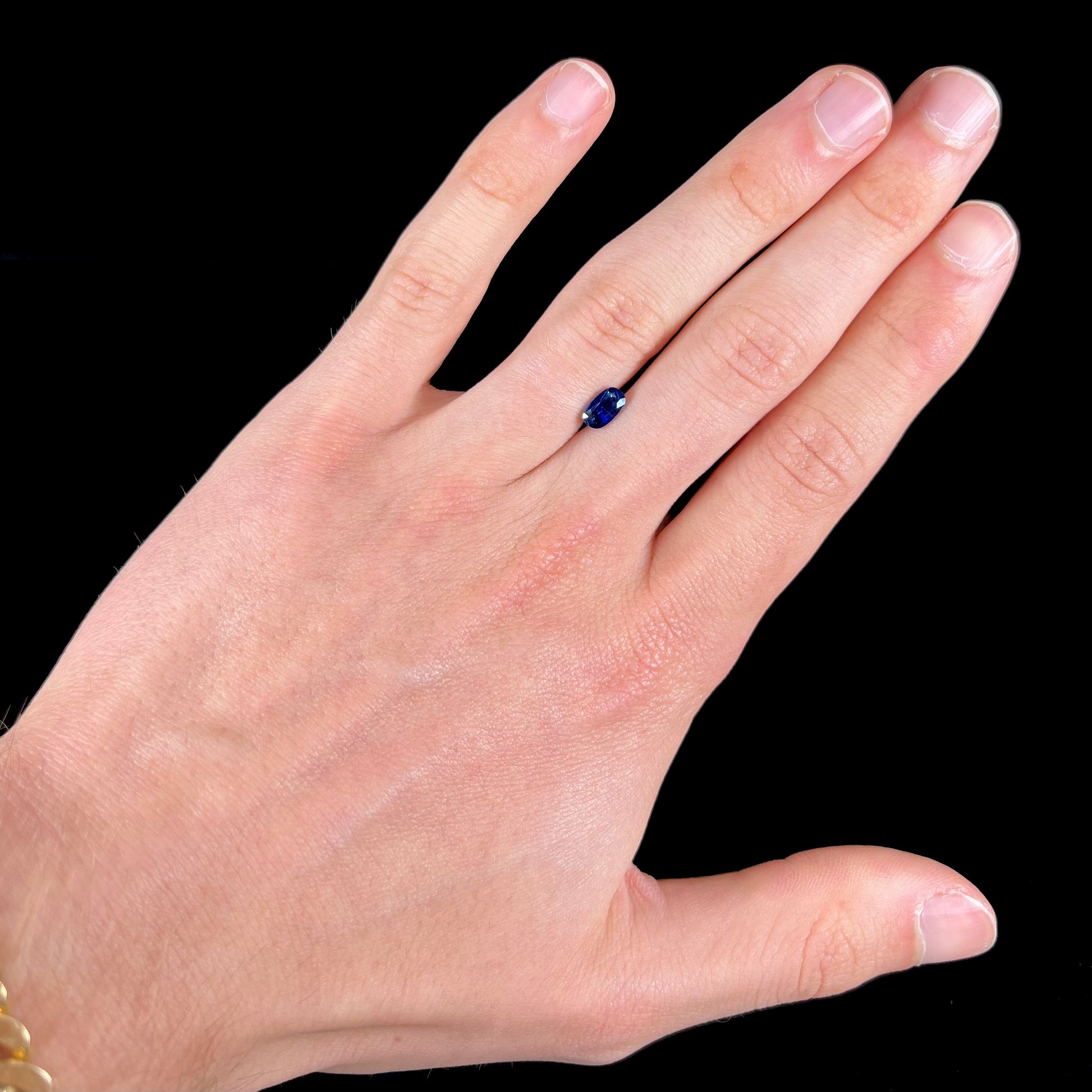 A loose, elongated oval cut blue sapphire gemstone.