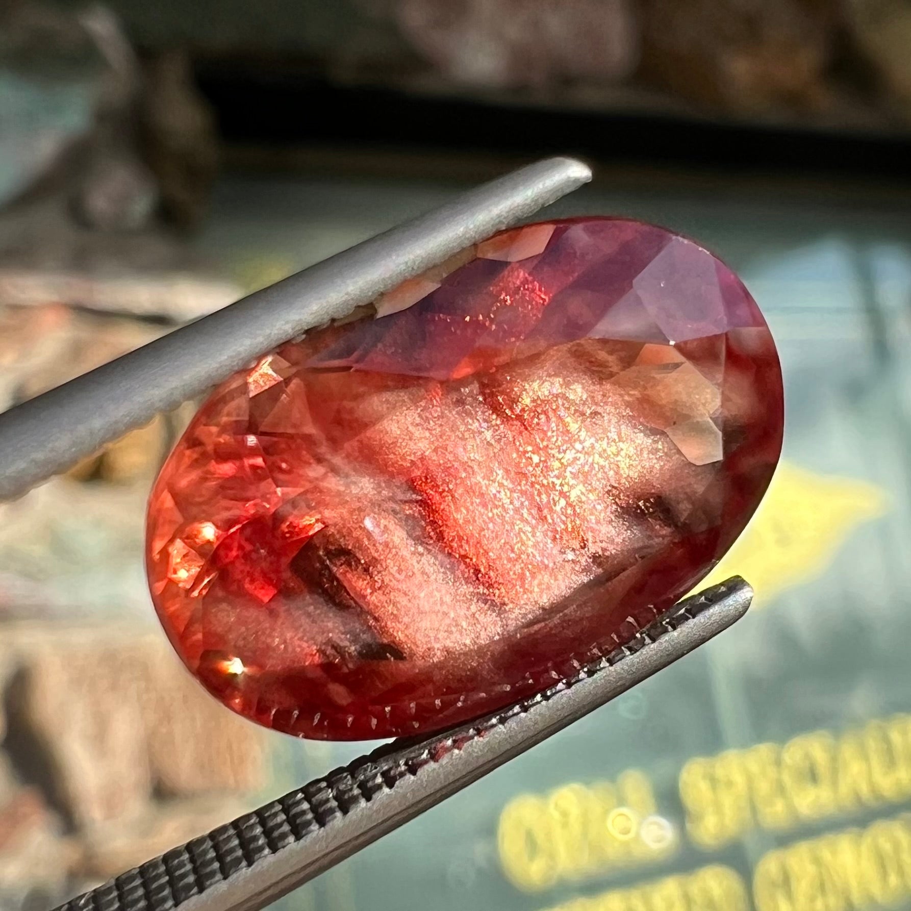 A faceted, oval cut sunstone.  The stone is red-orange color with a bright schiller flash.