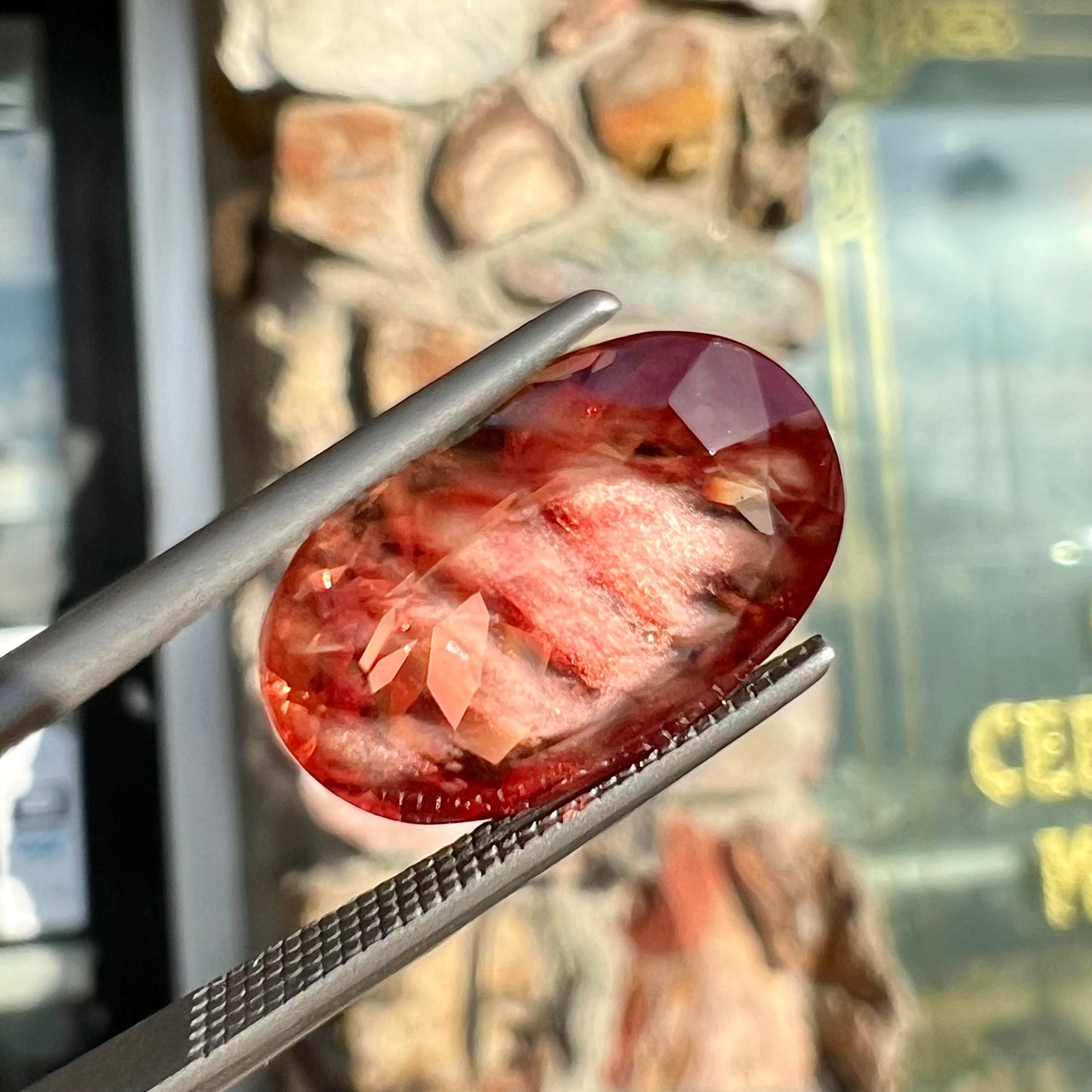 A faceted, oval cut sunstone.  The stone is red-orange color with a bright schiller flash.