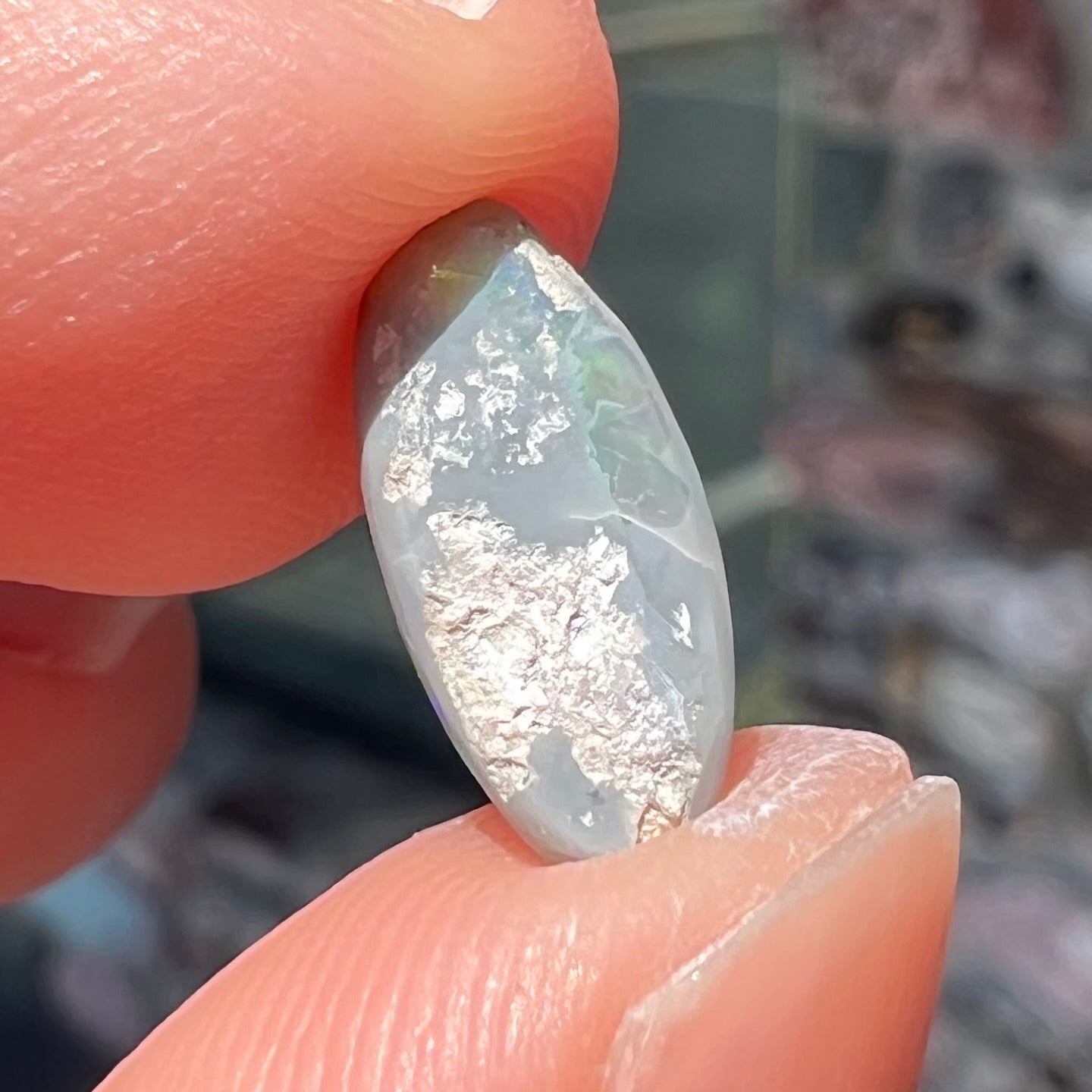 A loose, oval cabochon cut semi-black opal from Lightning Ridge, Australia.  The opal plays green and orange colors.