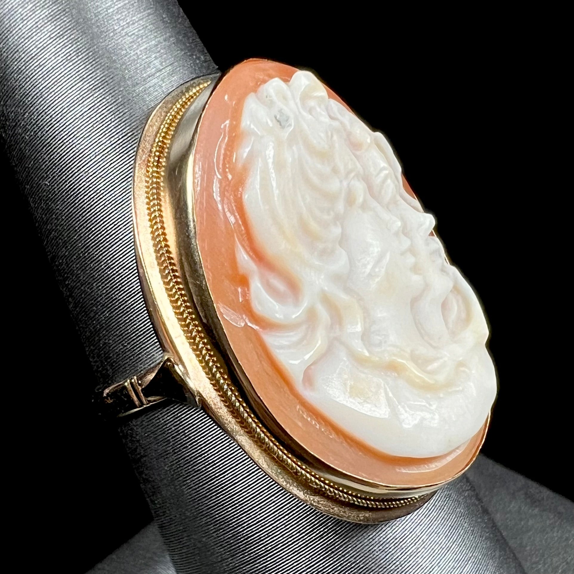 A ladies' vintage cameo solitaire ring in yellow gold.  The cameo is carved from shell and depicts the side profile of two womens' faces.