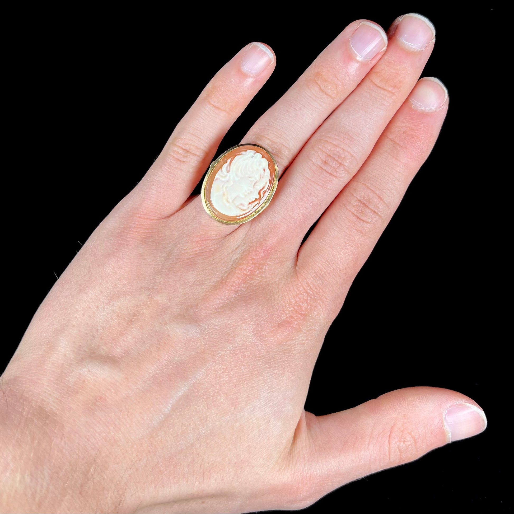 A ladies' vintage cameo solitaire ring in yellow gold.  The cameo is carved from shell and depicts the side profile of two womens' faces.