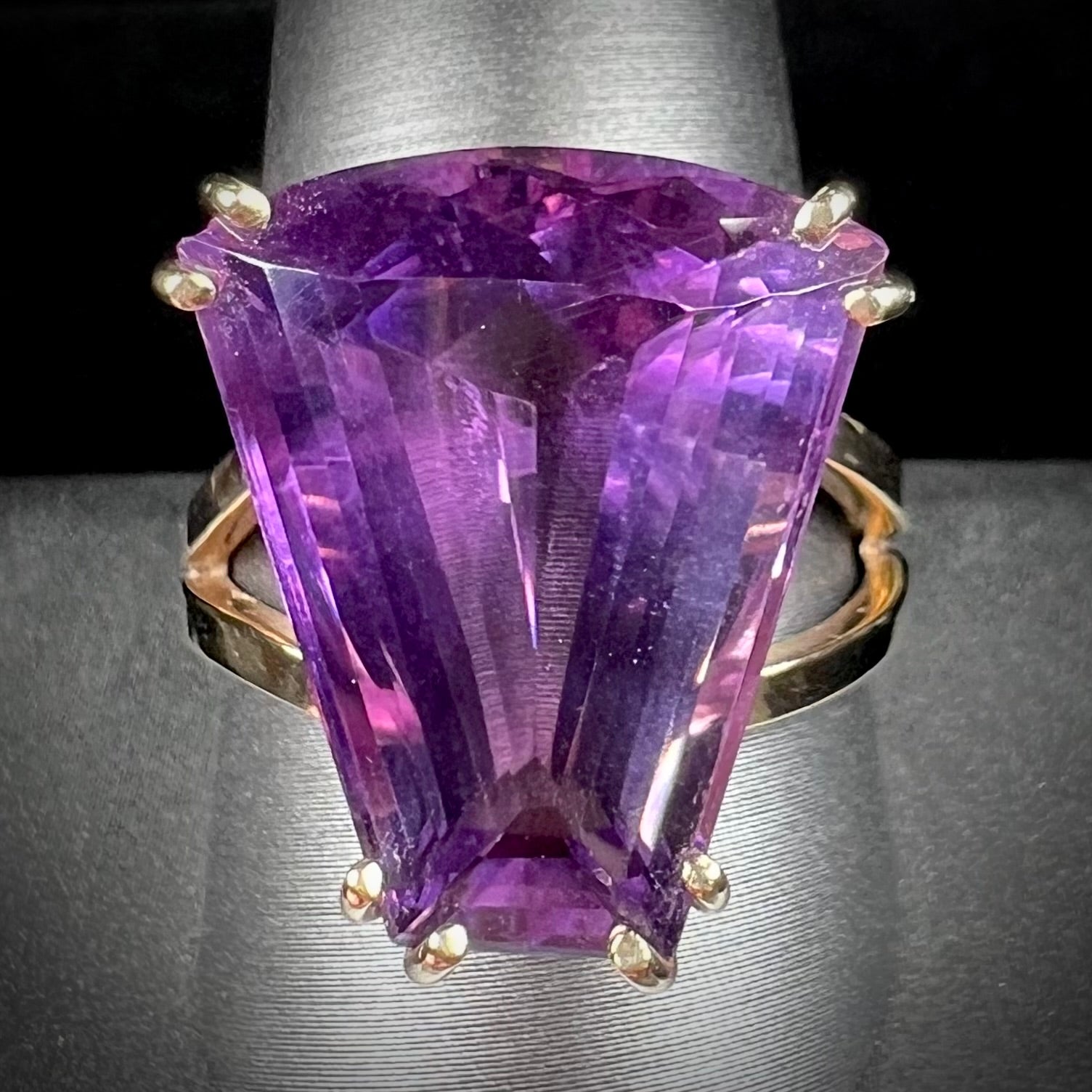 A ladies' yellow gold cocktail ring set with a shield cut purple amethyst gemstone.