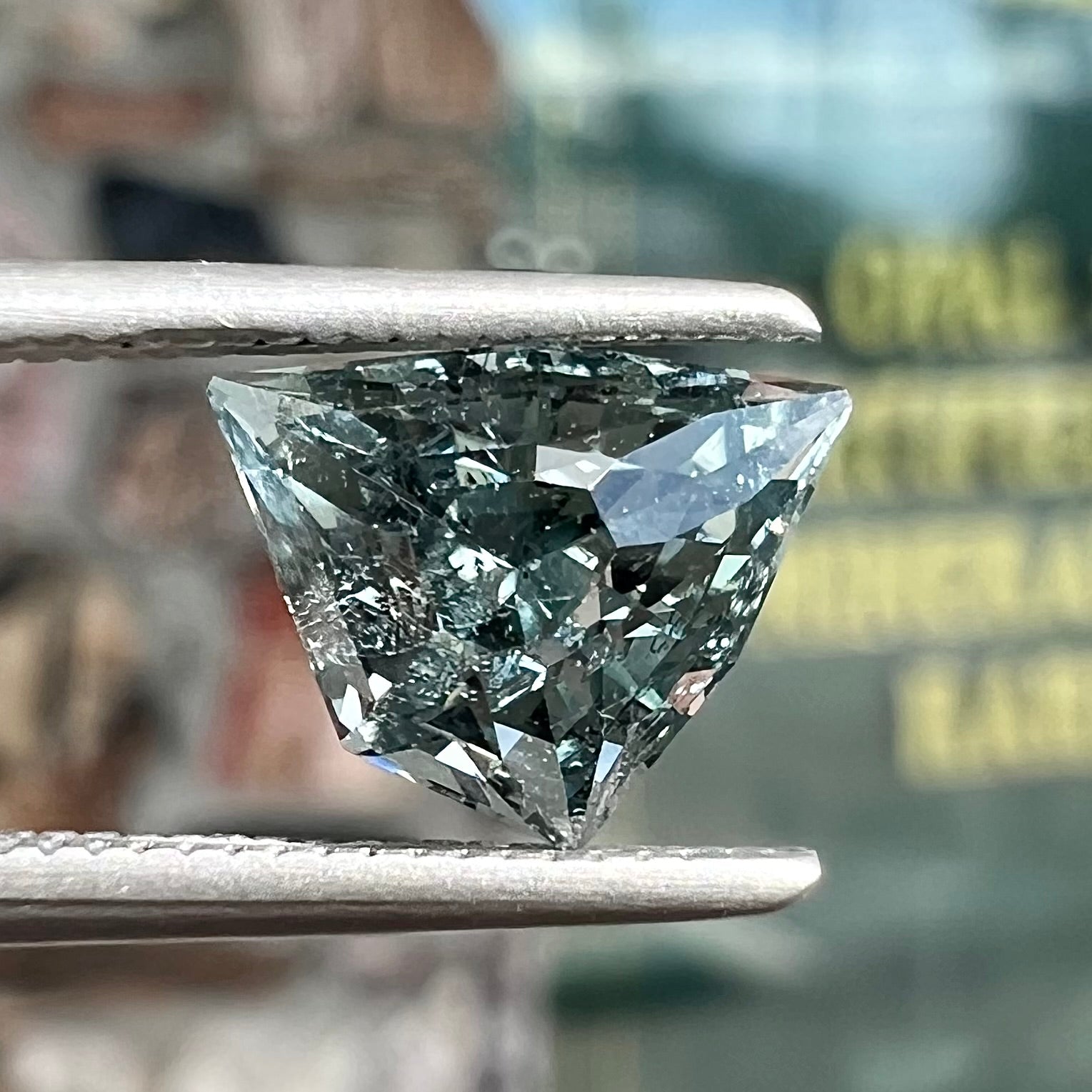 A loose, freeform shield cut tourmaline gemstone.  The stone is a steel blue color.