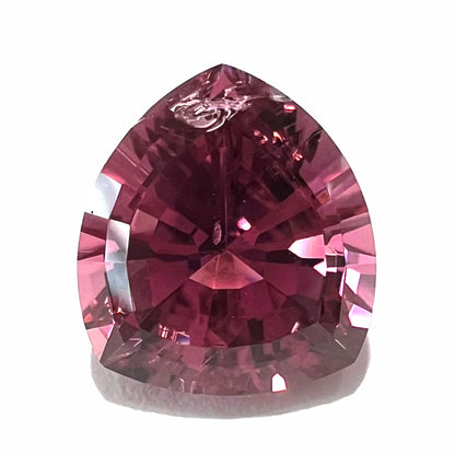 A loose, rounded trillion shield cut pink tourmaline gemstone.