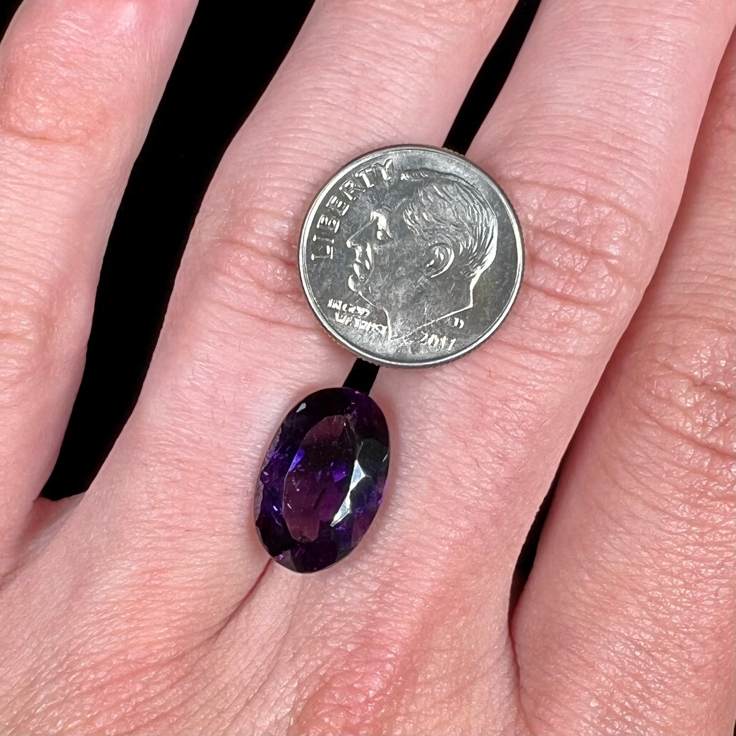 A loose, faceted oval cut Siberian amethyst gemstone.  The stone is purple color with blue and red flashes.