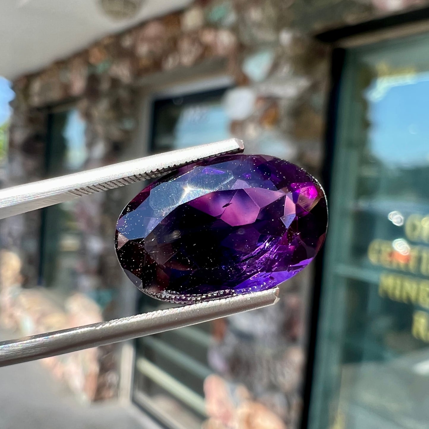 A loose, faceted oval cut Siberian amethyst gemstone.  The stone is purple color with blue and red flashes.