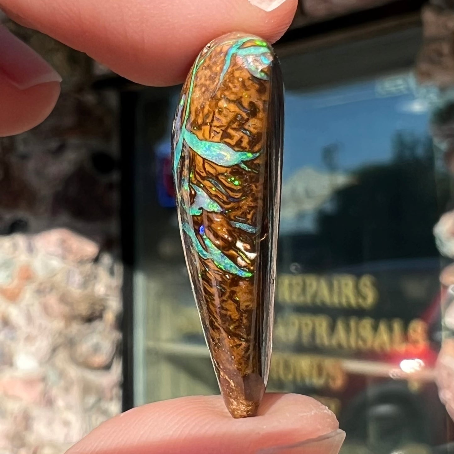A triangle shaped Koroit boulder opal.  The stone has blue veins of opal running through it.