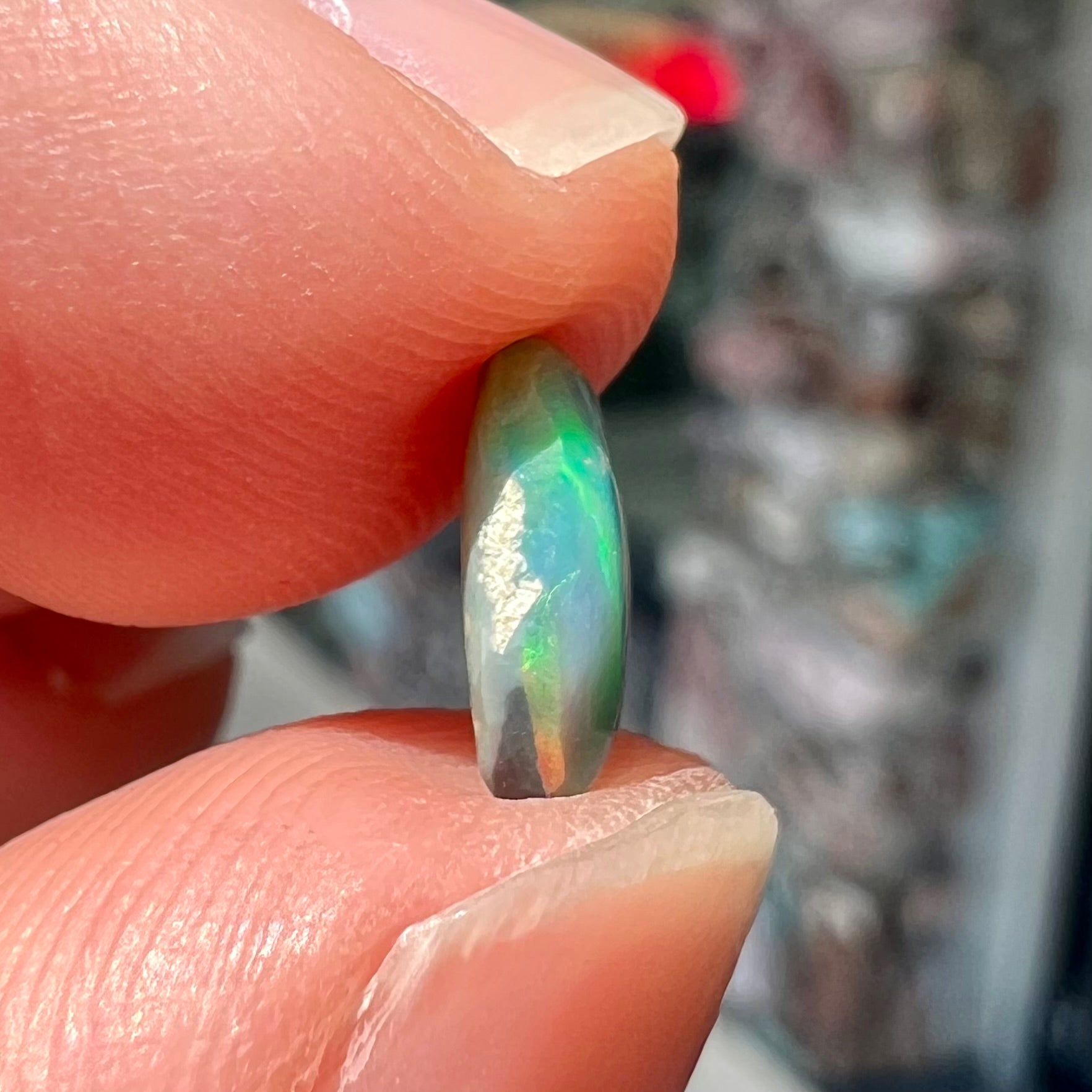 A loose, pill shaped black opal stone from Lightning Ridge, Australia.  The opal is green and blue.