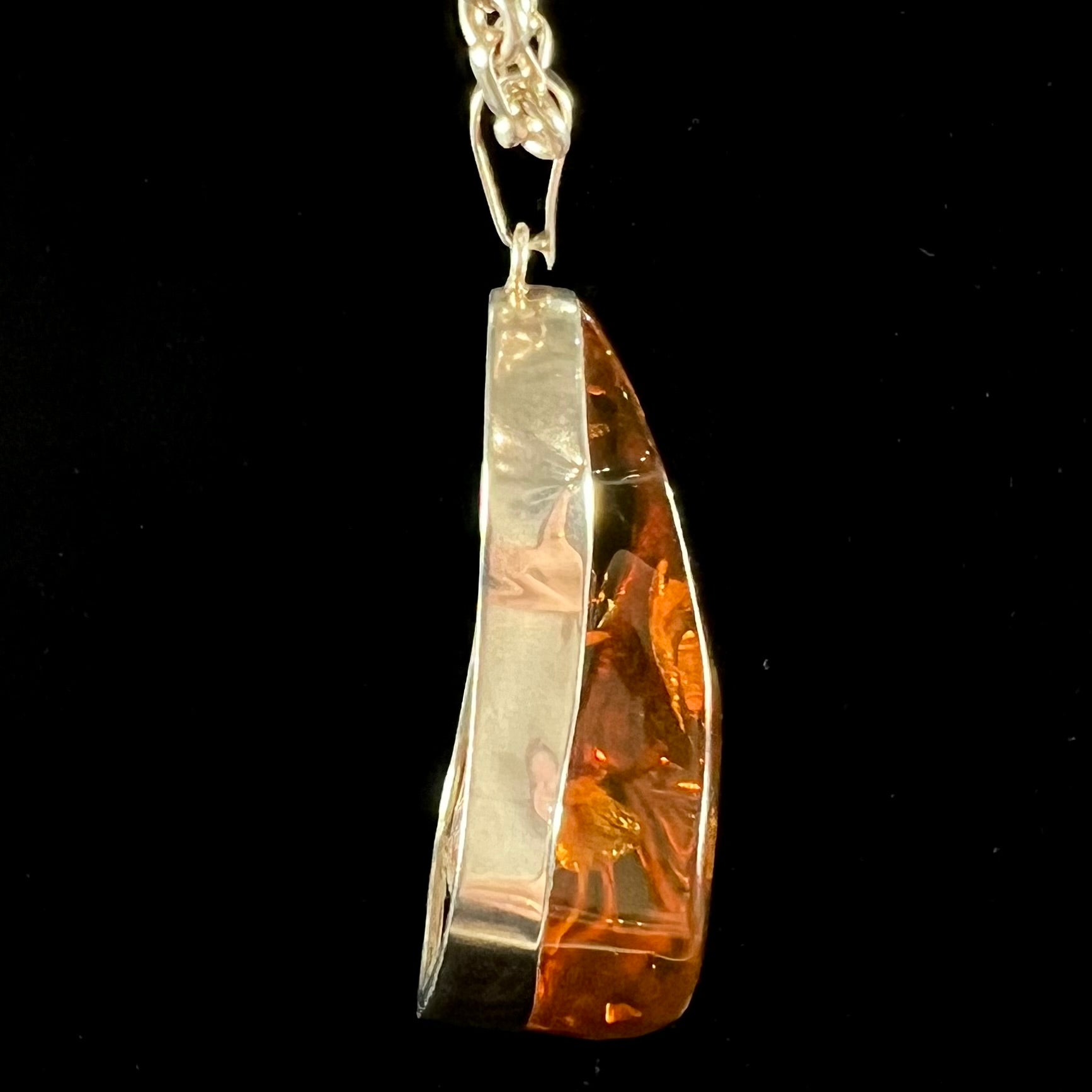 A sterling silver pendant set with a large natural amber stone.  The amber has sun spangled inclusions.
