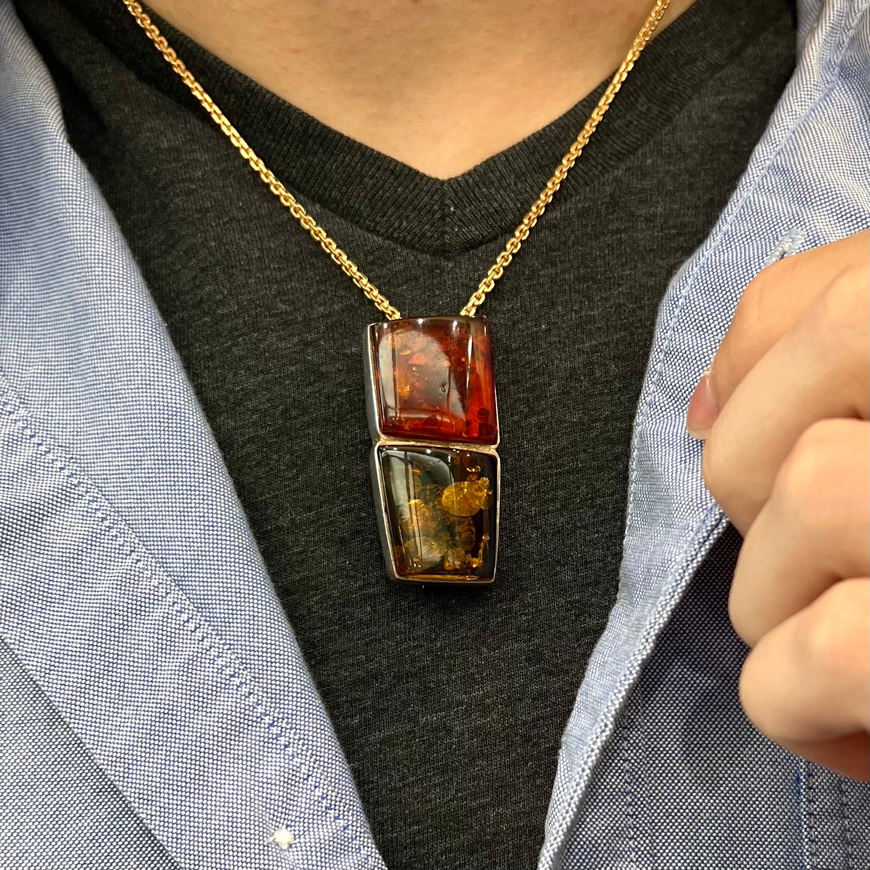 A sterling silver pendant brooch set with a red orange amber and a yellow sun-spangled amber.