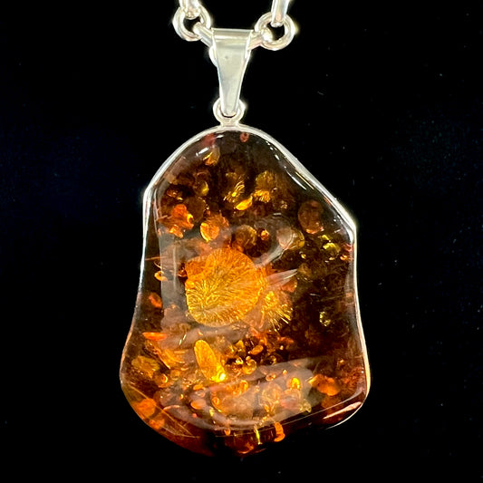 A sterling silver pendant set with a large natural amber stone.  The amber has sun spangled inclusions.