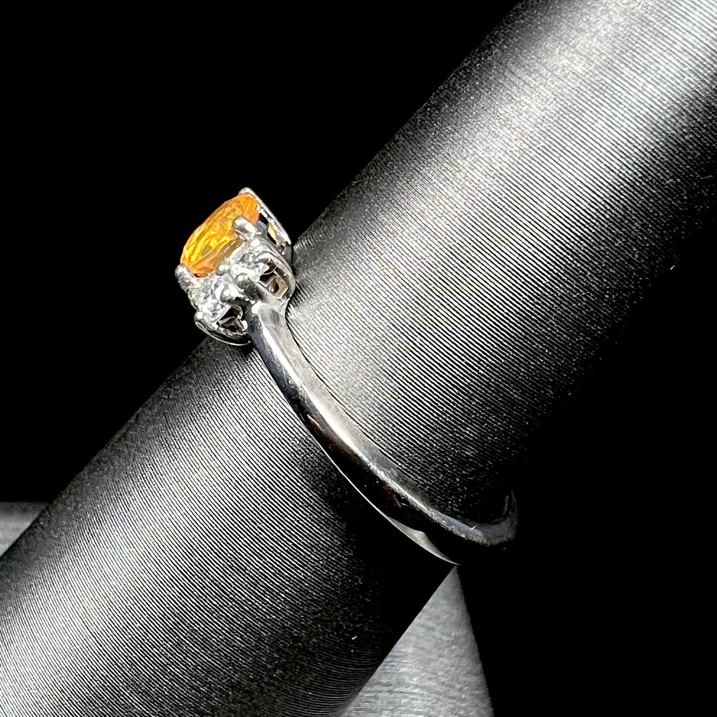 A ladies' sterling silver ring set with a faceted round cut fire opal and white zircon accents.