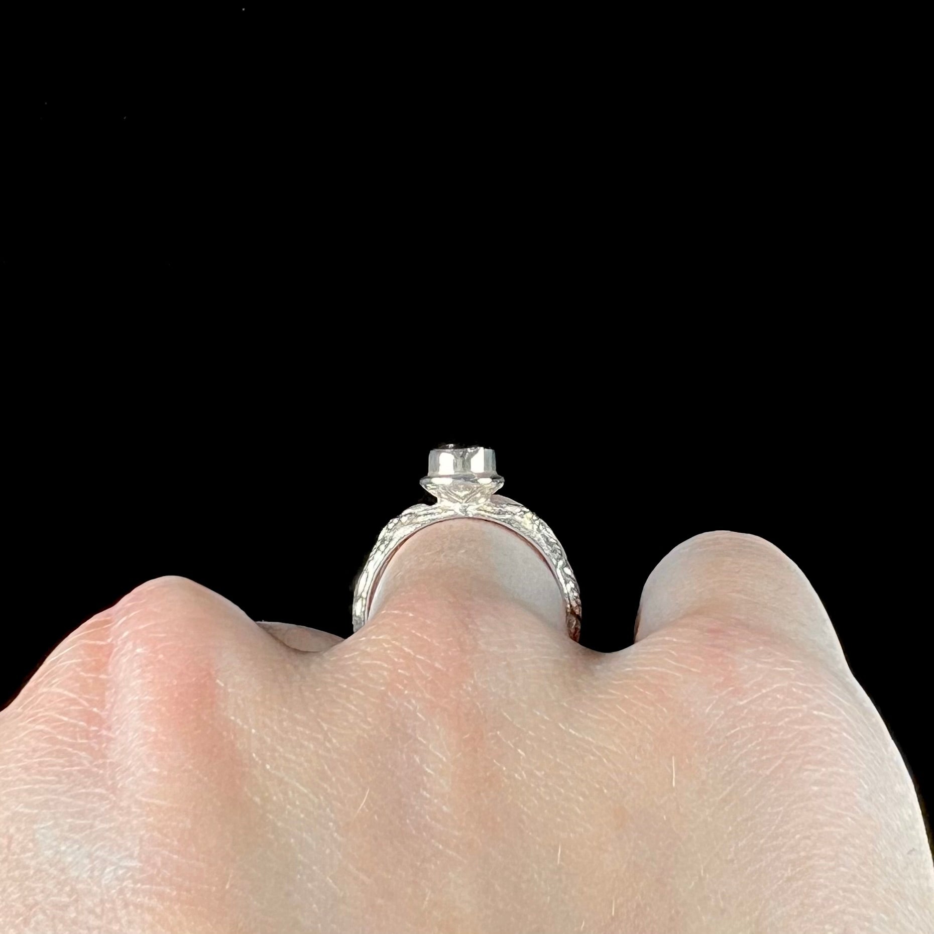 A ladies' sterling silver purple rhodonite garnet solitaire ring.  The shank has an etched floral leaf design.