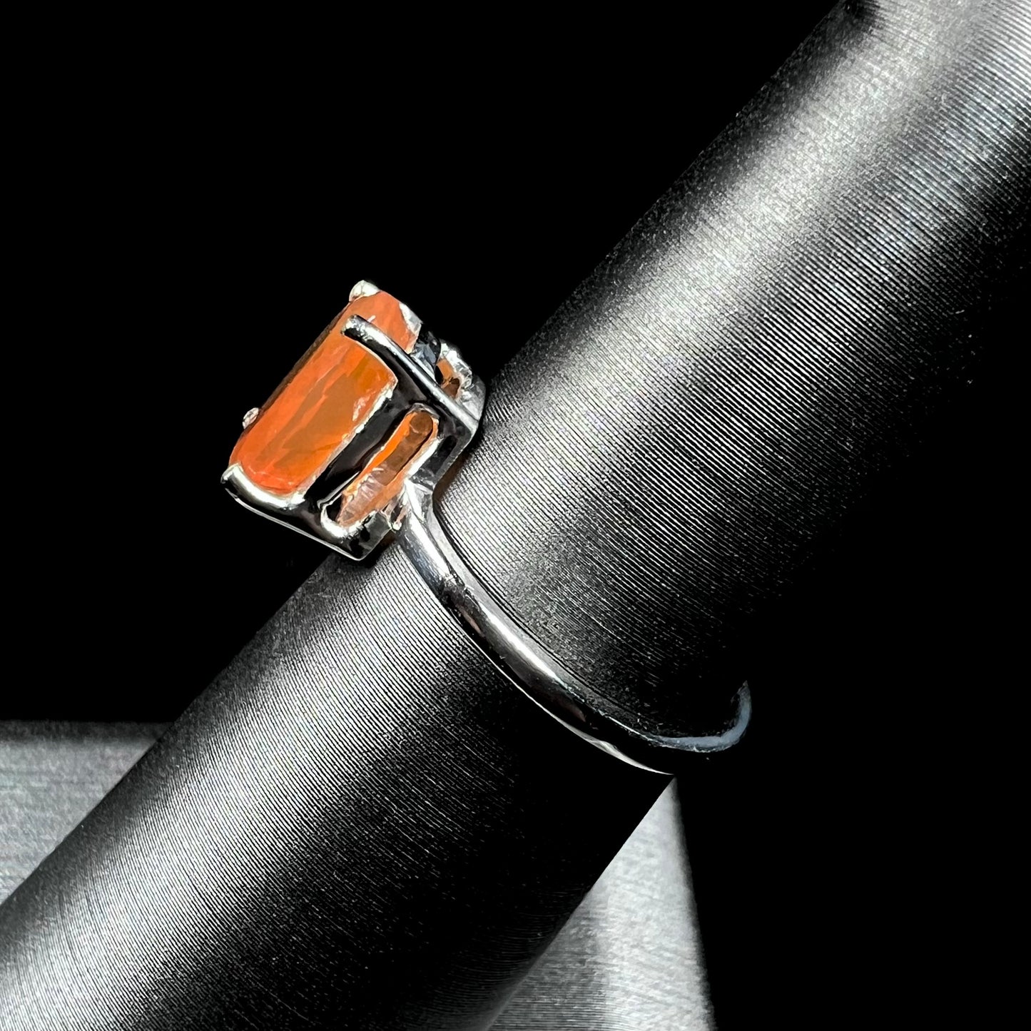 A silver solitaire ring set with a natural, faceted oval cut Mexican fire opal.  The stone is a bright orange color.