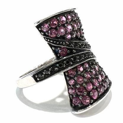 A ladies' bow-shaped designer ring pave set with purple rhodolite garnets and black spinel accents.