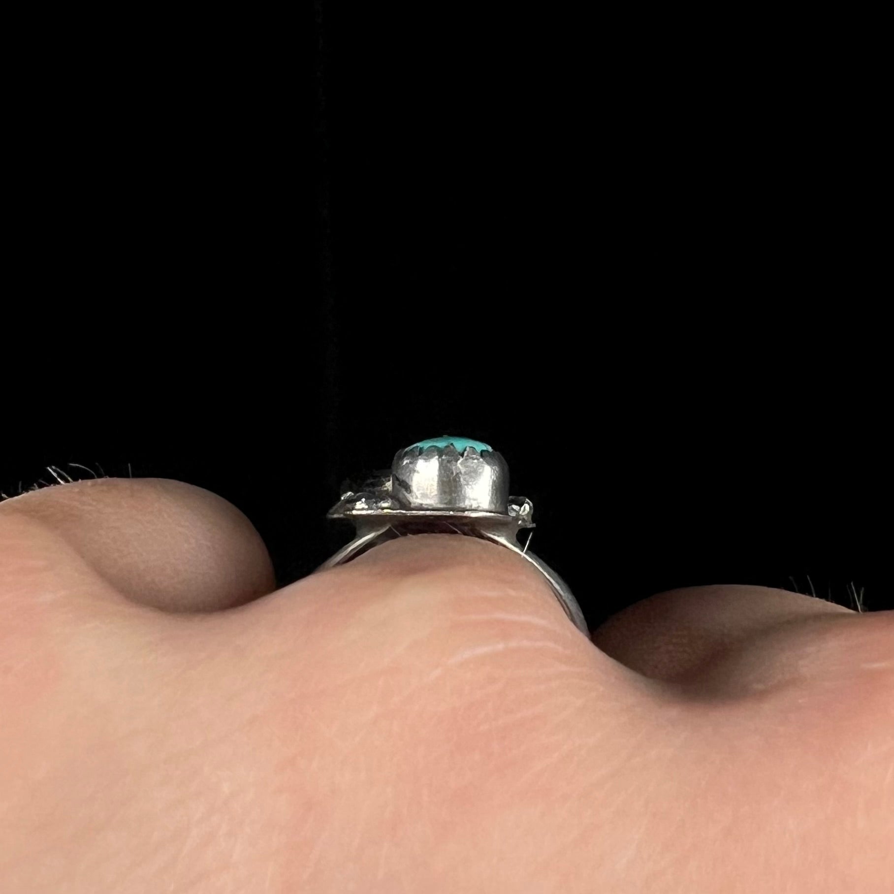 A vintage sterling silver Navajo style ring set with turquoise and coral stones and a feather design.