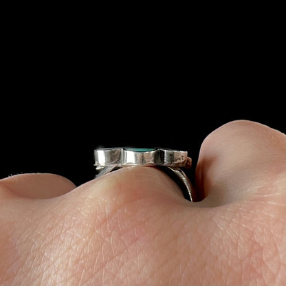 A vintage, sterling silver Zuni thunderbird ring inlaid with turquoise, mother of pearl, onyx, and coral stones.