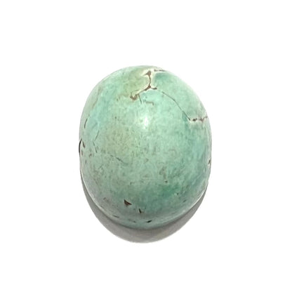 A loose, oval cabochon cut turquoise stone from the Sleeping Beauty Mine in Arizona.  The stone is a greenish blue color.
