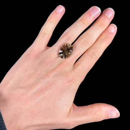 A loose, faceted oval laser cut smoky quartz gemstone.