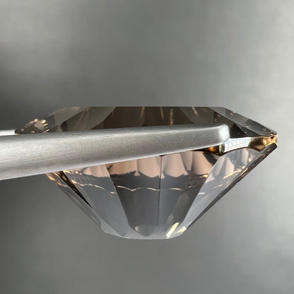 A loose, faceted oval laser cut smoky quartz gemstone.