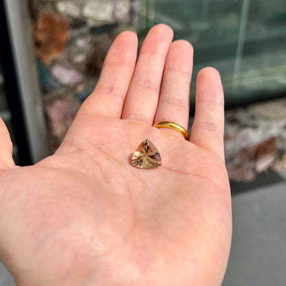 A loose, trillion cut smoky citrine gemstone.  The stone is a light golden brown color.