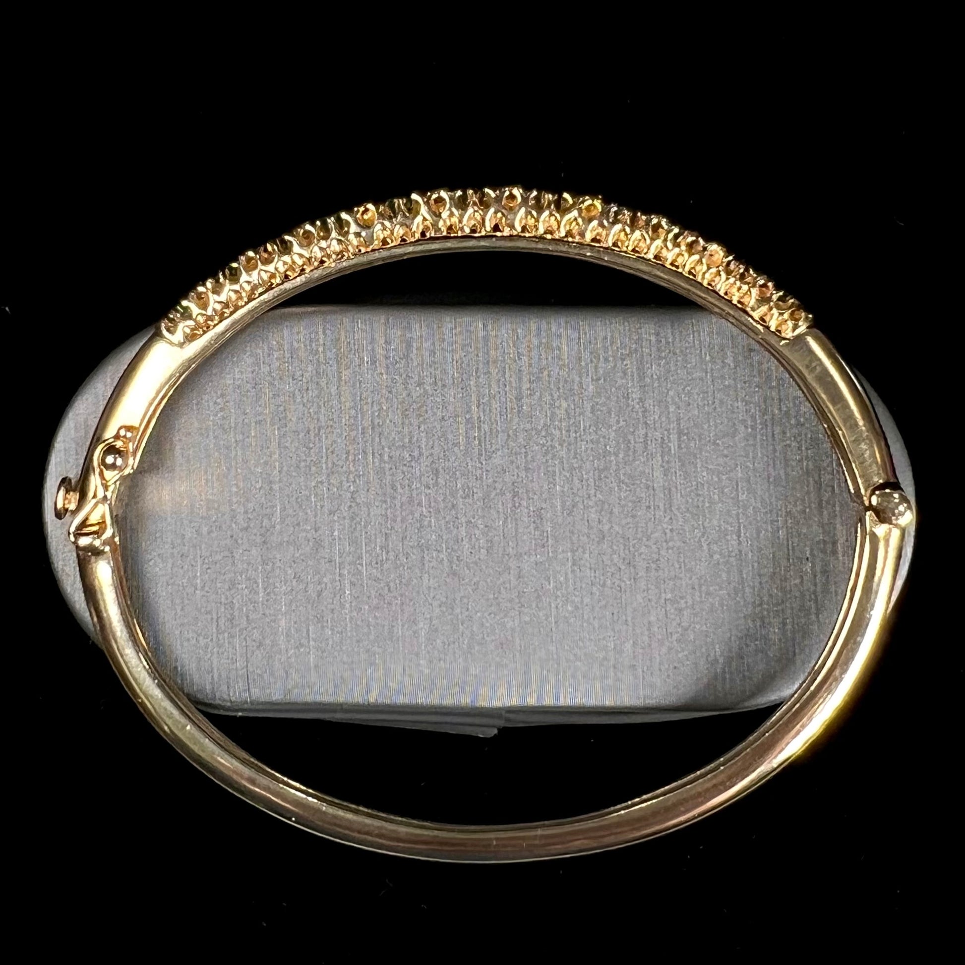 A ladies' yellow gold bangle bracelet set with round cut emeralds and diamonds.