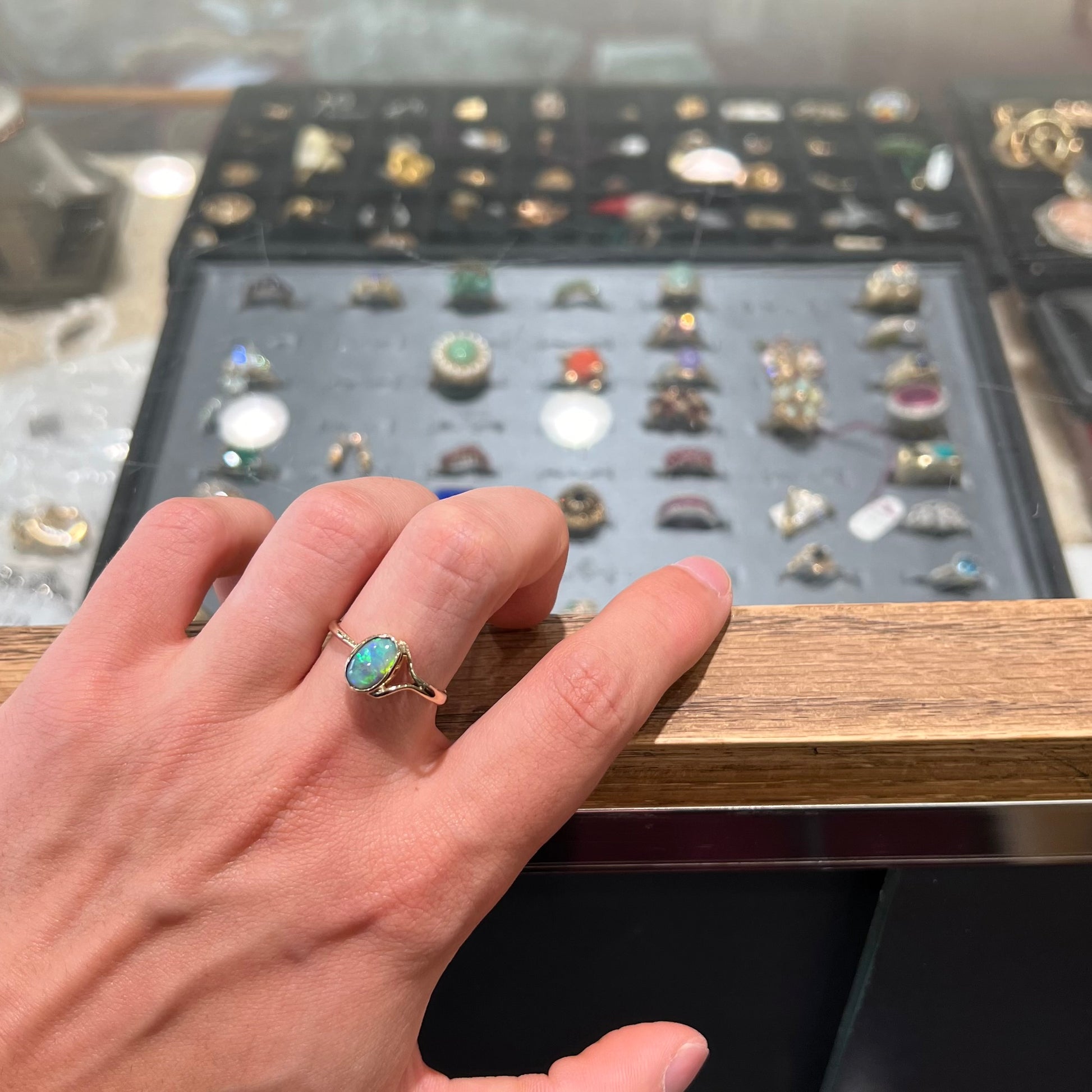 A ladies' oval cut black crystal opal solitaire ring handmade with a single split shank in yellow gold.