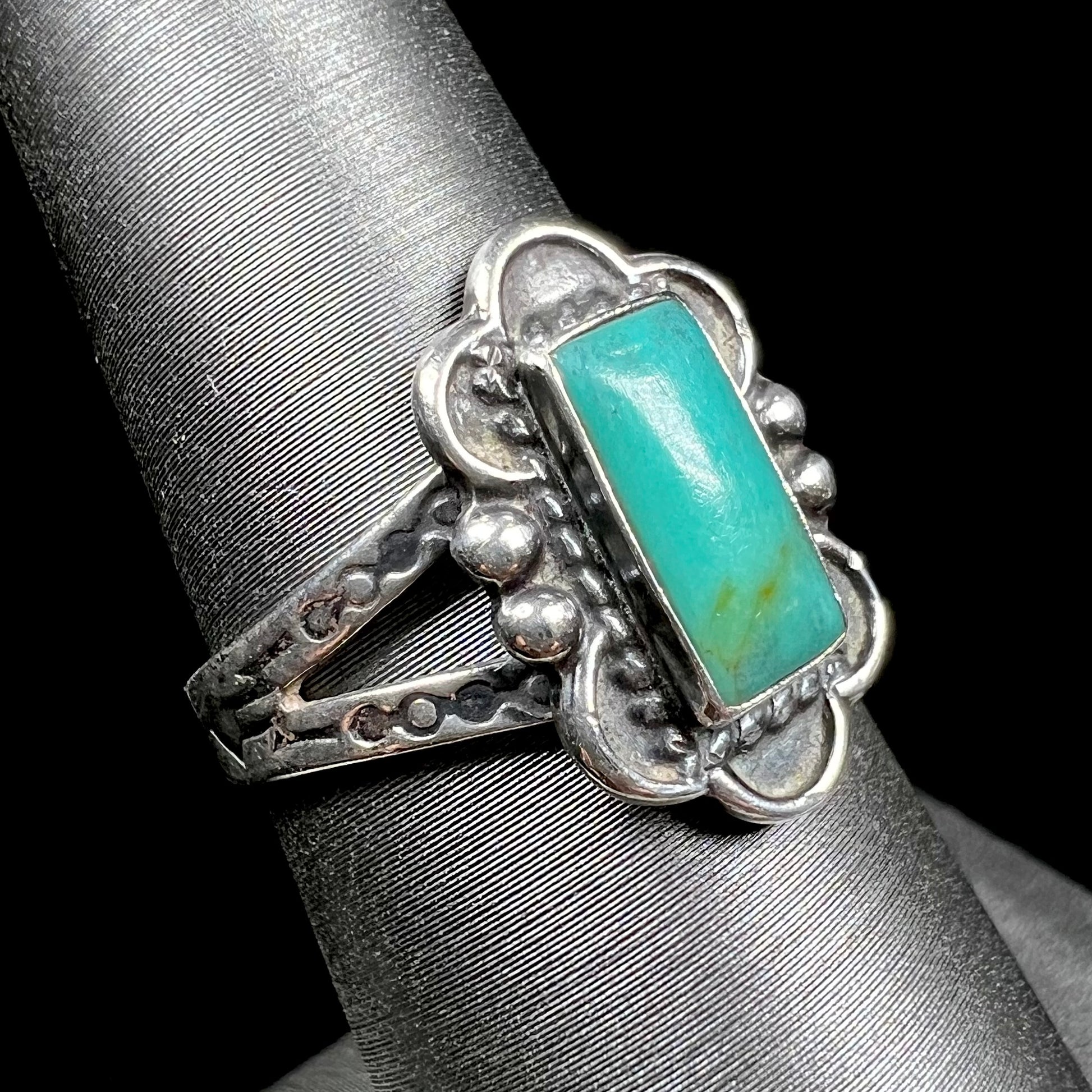 A ladies' silver ring stamped with Southwest style designs and set with a rectangular cabochon cut Royston turquoise stone.